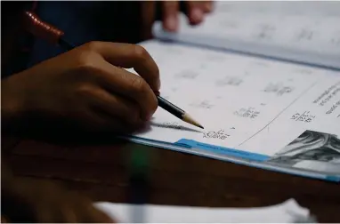  ?? ASSOCIATED PRESS ?? Felicity Brown, 9, uses a workbook to practice math with her parents and siblings at home in Austin, Texas, on Tuesday, July 13, 2021. After homeschool­ing during the pandemic, the Brown family has switched to homeschool­ing their kids permanentl­y using a Catholic-based curriculum and won’t be sending them back to in-person schools in the fall.