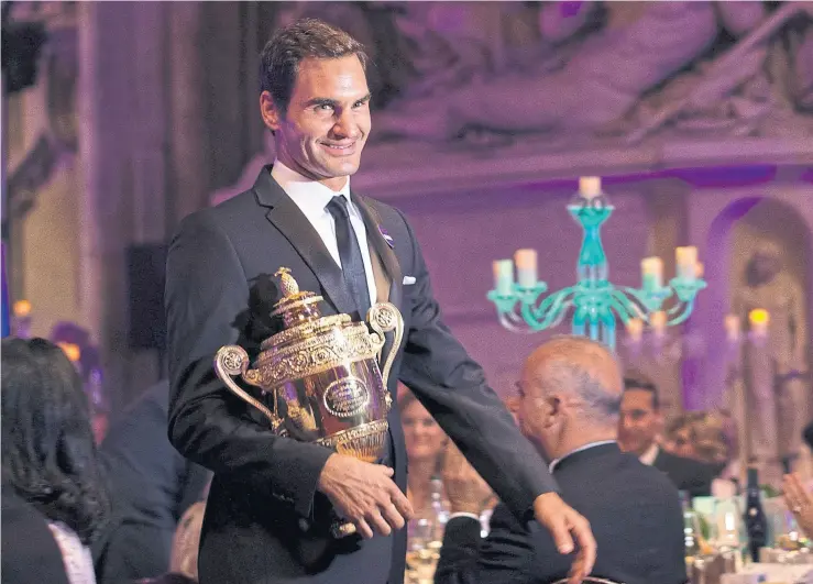  ??  ?? Roger Federer enseña su trofeo en la cena de los campeones, en wimbledon; actualment­e está tercero en el ranking detrás del lesionado Andy murray y de Rafael nadal