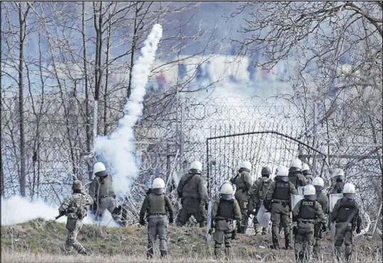  ?? Giannis Papanikos The Associated Press ?? Greek police officers guard a border fence in Kastanies as migrants gather on the Turkish side during clashes on Saturday.