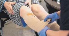  ?? FOTO: JANA BAUCH/DPA ?? Eine Pflegerin bandagiert die Beine eines alten Mannes. In den vergangene­n zehn Jahren sind die Löhne in der Branche stark gestiegen.