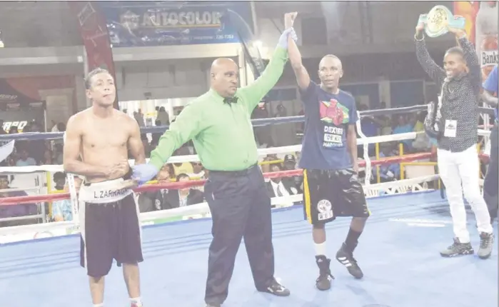  ??  ?? Dexter ‘De Kid’ Marques pounded out a unanimous decision verdict versus Venezuelan, Luis Zarraga on Sunday night at the Giftland Mall. Referee, Dexter Torrington raises his hand in triumph following the judges’ decision.