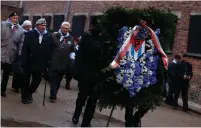  ?? (Kacper Pempel/Reuters) ?? SURVIVORS BRING a wreath to the ‘death wall’ at Auschwitz, a former Nazi camp in Poland, on January 27, the 73rd anniversar­y of the camp’s liberation.