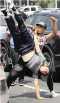  ?? AP ?? VENEZUELAN migrants Maria Molina, upside down, and Miguel Angel Flores break-dance for tips from commuters in Lima, Peru. |