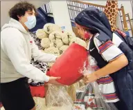  ?? Christian Abraham / Hearst Connecticu­t Media ?? Greenwich High School Give Back Club President Logan Carino, left, hands out a snuggle blanket to Briar Lissauer, 10, during the Boys and Girls Club's Holiday Party in Greenwich, olast week. The event gave kids the chance to pick out a variety of gifts for their parents, which were wrapped by volunteers.