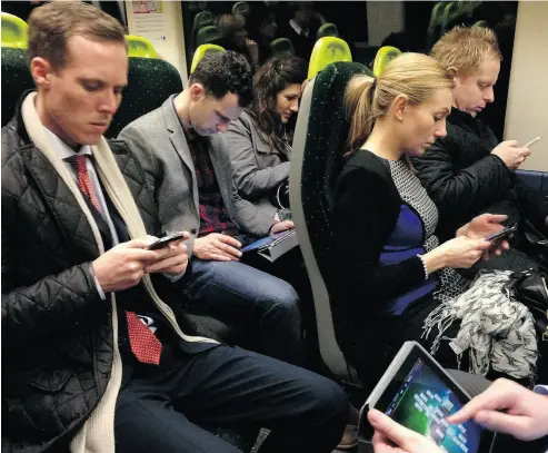  ?? JOHN KEEBLE / GETTY IMAGES ?? Social isolation: Commuters immersed in their mobile phones and tablets, texting and playing games.