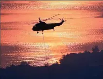  ?? The Associated Press ?? A helicopter hovers over a reservoir to fill a bucket with water as the fight against wildfires in California continues.