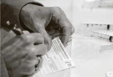  ?? Matt Slocum / Associated Press ?? A Chester County health department worker fills out a vaccinatio­n record card before administer­ing the Moderna vaccine to emergency medical and health care personnel last month inWest Chester, Pa.