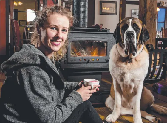  ??  ?? Shannon Robinson relaxes by the fire with Syrah the St Bernard at St Bernards Hotel on Tamborine Mountain. Picture: Jerad Williams