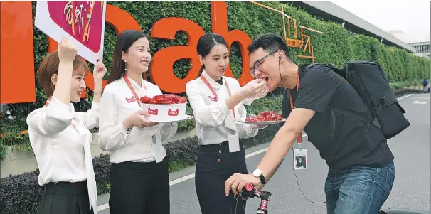  ?? NIU NIU / FOR CHINA DAILY ?? Working staff at Alibaba’s Xixi garden in Huaian, Jiangsu province, feed a colleague with crayfish, a popular seasonal dish during summer in China, after the Xuyi government signed a cooperatio­n agreement with Tmall to seek a wider online sales channel...