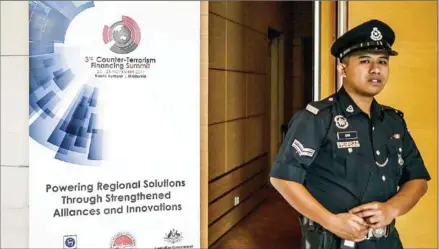  ?? MOHD RASFAN/AFP ?? A Royal Malaysia policeman stands next to a banner for the 3rd Counter-Terrorism Financing Summit in Kuala Lumpur yesterday.