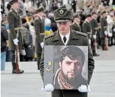  ?? SERGEI SUPINSKY AFP VIA GETTY IMAGES ?? A soldier holds a portrait of Dmytro Kotsiubail­o, a Ukrainian serviceman killed in combat in Bakhmut, during a memorial ceremony in Kyiv on Friday.