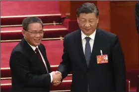  ?? (AP/Mark Schiefelbe­in) ?? Newly elected Premier Li Qiang (left) shakes hands with Chinese President Xi Jinping during a session of China’s National People’s Congress at the Great Hall of the People in Beijing. Video at arkansason­line.com/312liqiang/.