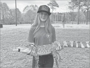  ?? Adam Carey ?? Emma Knowles of Cedartown holds a 6-month-old alligator in Ridge Ferry Park on Wednesday, April 10. Knowles, a seventh grader at Cedartown Middle , was in the park with her dad and little brother.