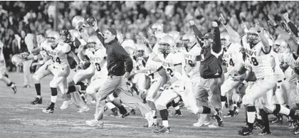  ?? MICHAEL CONROY/ASSOCIATED PRESS ?? The Navy bench storms the field at Notre Dame Stadium in 2007 after defeating the Fighting Irish 46-44 in triple overtime.