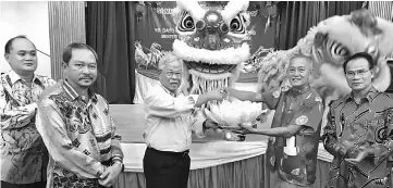  ??  ?? Fong presents Manyin (third left) with a cabbage designed in the shape of a flower, produced by the lion dance troupe. Looking on from right are Raymond, Jonathan and Lim.