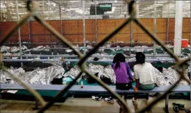  ?? The Associated Press ?? Two girls watch television from their holding area where hundreds of mostly Central American immigrant children were being processed at the U.S. Customs and Border Protection Nogales Placement Centre in Nogales, Ariz., in this June 18, 2014, file photo.