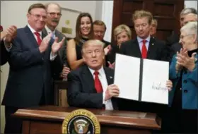  ?? EVAN VUCCI — THE ASSOCIATED PRESS ?? President Donald Trump shows an executive order on health care that he signed in the Roosevelt Room of the White House on Thursday.