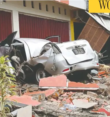  ?? ANTARA FOTO/AKBAR TADO VIA REUTERS ?? A crushed car sits in rubble after a 6.2-magnitude earthquake killed dozens of people on the Indonesian island
of Sulawesi on Friday. The temblor also damaged more than 300 homes, two hotels and flattened a hospital.