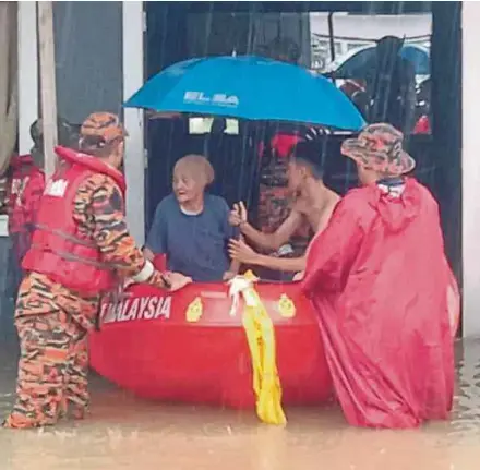  ?? PIC COURTESY OF FIRE AND RESCUE DEPARTMENT ?? Fire and Rescue Department personnel evacuating a woman in Kampung Sinar Budi Baru, Batu Kawa, Kuching, yesterday.