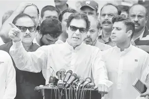  ?? — Gambar Reuters ?? TURUT BERTANDING: Khan (tengah) bercakap di hadapan anggota media selepas membuang undi di balai undian semasa pilihan raya umum berlangsun­g di Islamabad semalam.