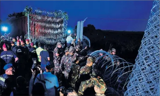  ??  ?? El ejército húngaro coloca el último tramo de la valla de espino en la frontera con Serbia