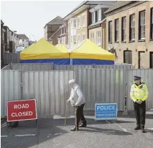  ?? AP FILE PHOTO ?? SEARCH PROCESS: A man walks by as British police officers guard metal fencing surroundin­g tents set up by search teams in Salisbury, England.