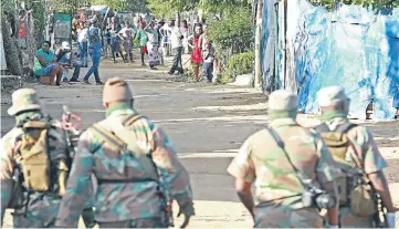  ??  ?? On a Diepsloot street, soldiers approach people who are demonstrat­ing a loose interpreta­tion of social distancing.