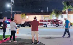  ?? ALLISON ZAUCHA/THE NEW YORK TIMES ?? Onlookers gather at the scene of a mass shooting Wednesday in Orange, California. Four people, including a 9-year-old boy, were killed.