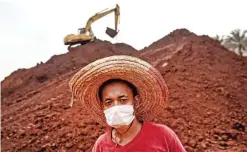  ??  ?? BUKIT GOH: A worker wearing a face mask looks on at a bauxite storage site in Bukit Goh situated in Malaysia’s rural state of Pahang. — AFP