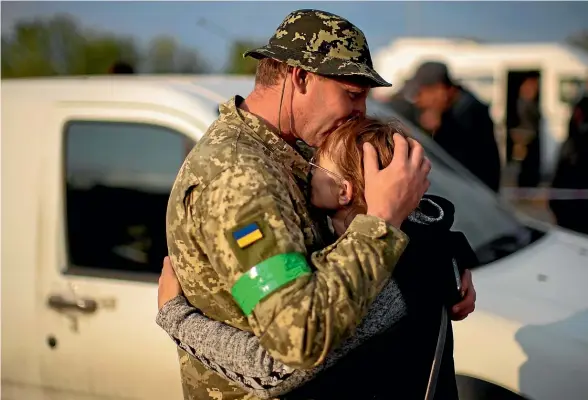  ?? AP ?? Hryhorii hugs his wife Oksana as they are reunited at a reception centre for displaced people in Zaporizhzh­ia on Monday. Thousands of Ukrainian continue to leave Russian occupied areas.