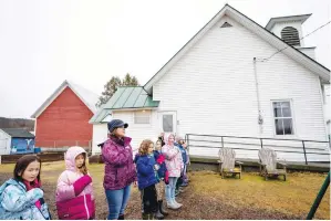  ?? (AP Photo/david Goldman) ?? Classroom aid Ericka Bellavance, third from left, leads students in the Pledge of Allegiance outside the Elmore School, the last one-room schoolhous­e in the state, March 6 in Elmore, Vt. In Elmore, population 886, its residents are used to holding tight to traditions. They’ve fought to keep open their post office, their store and their school. Last fall, Elmore residents voted 2-1 in favor of keeping their town meetings.