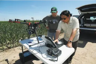  ?? Photos by David Zalubowski / Associated Press ?? Department of Agricultur­e intern Alex Olsen (left) and engineerin­g technician Kevin Yemoto set up a drone for flight over a research farm northeast of Greeley, Colo. Below: Huihui Zhang from the Department of Agricultur­e talks about efforts to use technology at the farm.