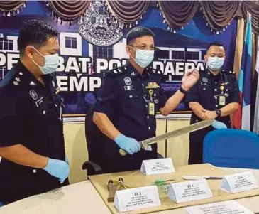  ?? PIC BY ABDUL RAHEMANG TAIMING ?? Semporna police chief Superinten­dent Mohd Farhan Lee Abdullah holding up the parang used by a man to attack policemen in Kampung Panji Laut on Friday.