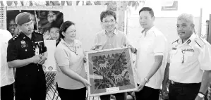  ??  ?? Anne (second from left) presenting a memento consisting of a handcrafte­d Dastar fabric to Ian while Raymond (middle) looks on.