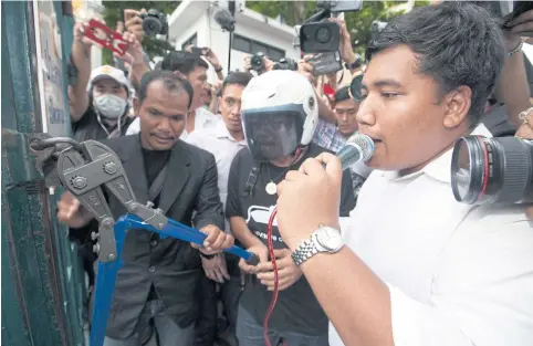  ?? LAOPAISARN­TAKSIN PAWAT ?? Anti-coup activist Sirawith ‘Ja New’ Seritiwat breaks a lock at Gate 3 to let demonstrat­ors in to join a gathering inside Thammasat University’s Tha Prachan campus.