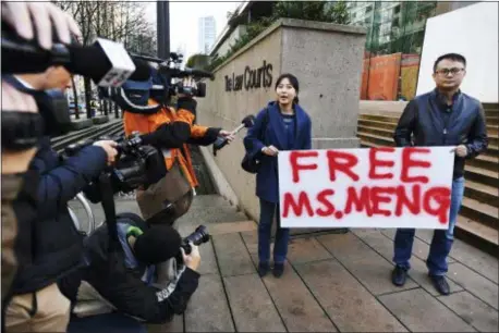  ?? JONATHAN HAYWARD — THE CANADIAN PRESS VIA AP ?? People hold a sign at a Vancouver, British Columbia courthouse prior to the bail hearing for Meng Wanzhou, Huawei’s chief financial officer on Monday. Meng Wanzhou was detained at the request of the U.S. during a layover at the Vancouver airport on Dec. 1.