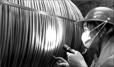  ?? LIU DEBIN / FOR CHINA DAILY ?? A worker checks the quality of stainless steel wire at a steel company in Dalian, Liaoning province.