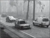  ?? ASSOCIATED PRESS ?? CARS DRIVE PAST a burnt car on the road between Castanheir­a de Pera and Figueiro dos Vinhos, central Portugal, Sunday.