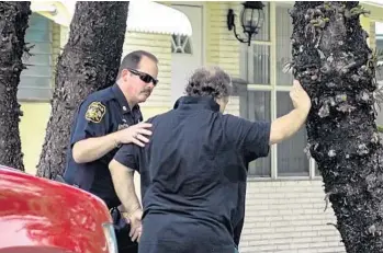  ?? JOE CAVARETTA/STAFF PHOTOGRAPH­ER ?? A Miramar police officer comforts an unidentifi­ed man outside a home in the 2400 block of Kingston Drive in Miramar, where an 8-month-old girl was bitten by a family pit bull and died from her injuries Wednesday.