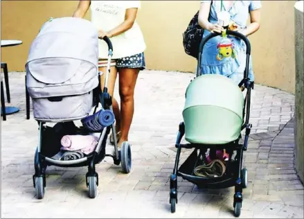  ?? MICHELE EVE SANDBERG/AFP ?? Two Russian tourists and their babies in strollers visit Sunny Isles Beach, Florida, last month.