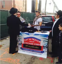  ?? (S.M. Weiss) ?? CHABAD STUDENTS put tefillin on fans outside Wrigley Field before the start of game 5 of the 2016 World Series (won by the beloved Cubbies in 7 games).