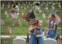  ?? KATIE GREENE — THE GRAND RAPIDS PRESS VIA AP ?? Natalie Benson, 5, and Holly Sweezer, 6, carry extra flags as Boy and Girl Scouts place flags on each of the 5,000 headstones at the Grand Rapids Veterans State Cemetery in Michigan.