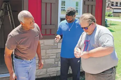  ?? CARA ANTHONY/KHN ?? University of Illinois Extension director Jody Johnson (right) exchanges contact informatio­n with Lee Wright (left) and his son Roman Wright.