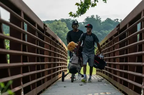  ?? Kevin D. Liles, © The New York Times Co. ?? Adrian Knight, left, and Jordan Colbert walk and carry their own clubs at Bobby Jones Golf Course in Atlanta on Aug. 11.