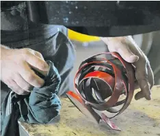  ??  ?? Mark Bellows wipes down a dusty piece of metal that belongs to a bigger piece called Ducati.