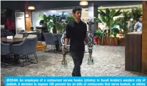  ?? — AFP ?? JEDDAH: An employee of a restaurant serves hooka (shisha) in Saudi Arabia’s western city of Jeddah. A decision to impose 100 percent tax on bills of restaurant­s that serve hookah, or shisha has sparked social media fury in Saudi Arabia, which seeks to boost its economy.