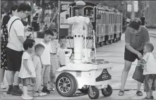  ?? ZOU XUNYONG / FOR CHINA DAILY ?? People check out a 5G intelligen­t robot patroller at a commercial area in Zhoushan, Zhejiang province, in October.