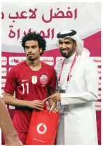  ?? (AFP) ?? Qatar’s forward Akram Afif (left) receives the Man of the Match award after the 24th Arabian Gulf Cup Group A match against the United Arab Emirates at the Khalifa Internatio­nal Stadium in Doha on Monday.