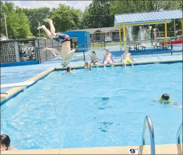  ?? (NWA Democrat-Gazette/Susan Holland) ?? Several teens work on their tan on the edge of Gravette’s pool while young Ethan Cooley, 12, of Siloam Springs, dives into the water. Cooley said he and his family come to Gravette to enjoy the pool since Siloam Springs’ water park has been closed.