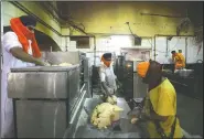  ??  ?? Volunteers put dough into a machine making chapati, thin unleavened bread.